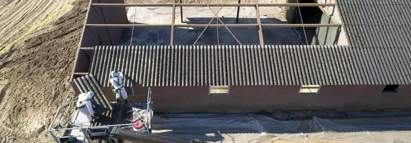 Désamianteurs au travail sur une toiture en plaques ondulées