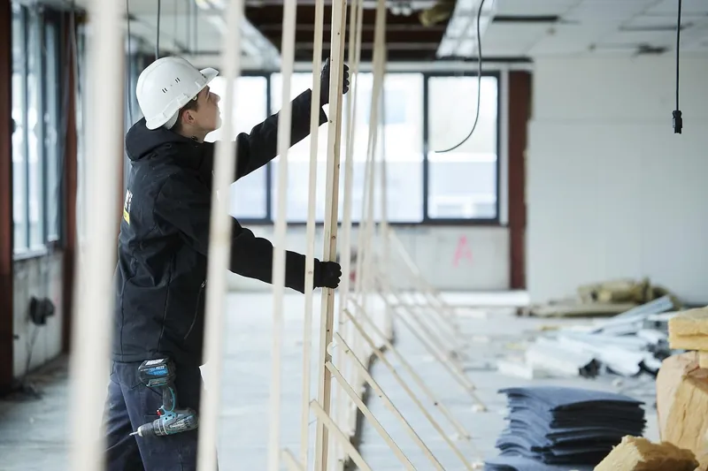 Un désamianteur monte l'ossature en bois d'une zone hermétique