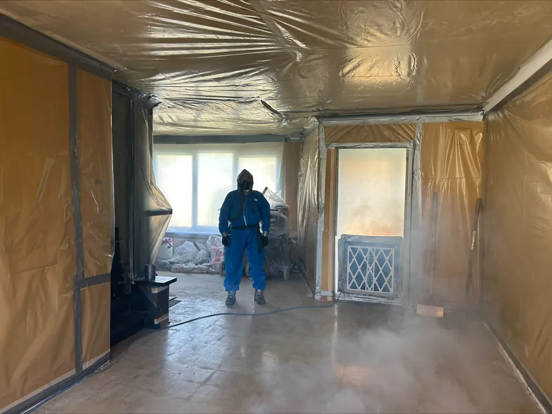 Local entièrement emballé sous film avec un désamianteur au travail